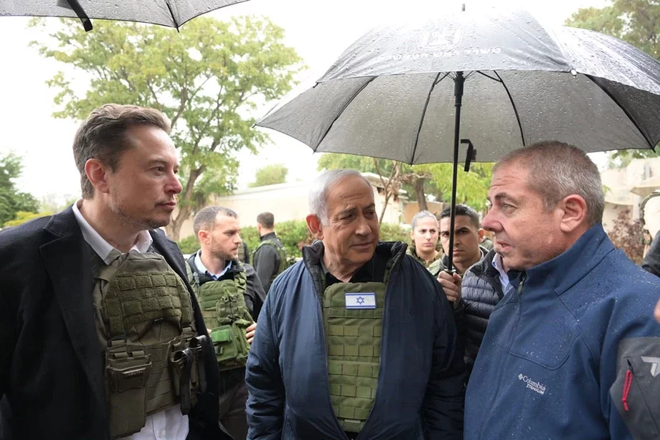 Ілан Маск (злева) і Біньямін Нетаньяху (пасярэдзіне) у кібуцы Кфар-Аза. Фота: Amos Ben-Gershom (GPO) Handout via Getty Images